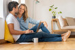 © steve brookland/Westend61 - Happy couple with laptop looking at each other while sitting at home office