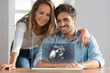 © steve brookland/Westend61 - Happy couple looking at ultrasound image over transparent screen at home