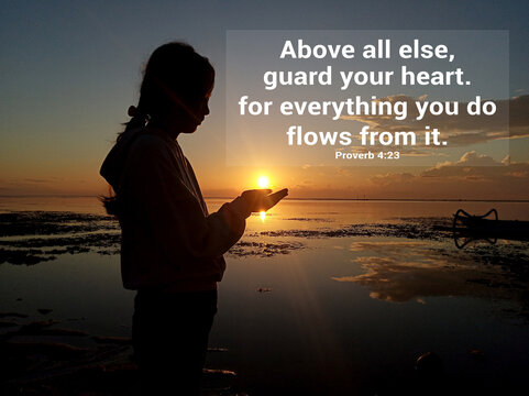 Wall Mural -  - Bible verse inspirational quote - Above all else, guard your heart, for everything you do flows from it. Proverb 4:23. Religious words with young girl silhouette holding light of sunrise in hands.