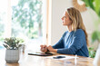 © steve brookland/Westend61 - Blond businesswoman writing in diary while sitting at table