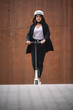 © SERGIO NIEVAS/Westend61 - Young businesswoman riding electric push scooter on footpath
