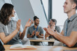 © Mareen Fischinger/Westend61 - Male and female trainees clapping while sitting on bench in training class
