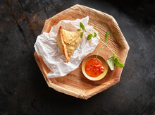 Studio Shot Of Wooden Coaster With Samosa Dumpling And Bowl Of Chili Sauce