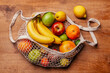 © Retales Botijero/Westend61 - Reusable cotton mesh bag with fresh fruits lying on wooden table