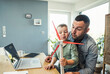 © Uwe Umstatter/Westend61 - Male freelancer with son blowing wind turbine while playing at home