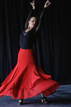 Dancer In Red Skirt Performing Flamenco On Black Background