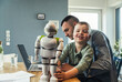 © Uwe Umstatter/Westend61 - Smiling boy playing with robot while father working on laptop at home