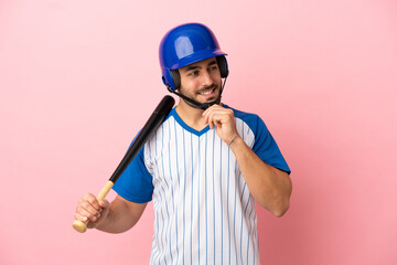 Wall Mural - Baseball player with helmet and bat isolated on pink background looking to the side and smiling