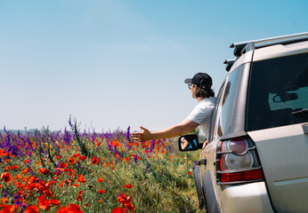 person in a car by colorful meadow in summer