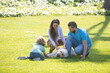 © Volodymyr - Family taking dog for walk in countryside. Outdoor portrait of happy family in summer park, young couple with child boy on grass.
