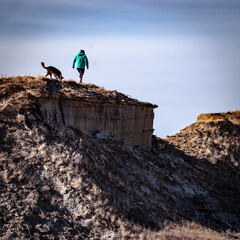 Poster - Closeup of a person and a dog on the cliff on a hiking trip on a sunny day