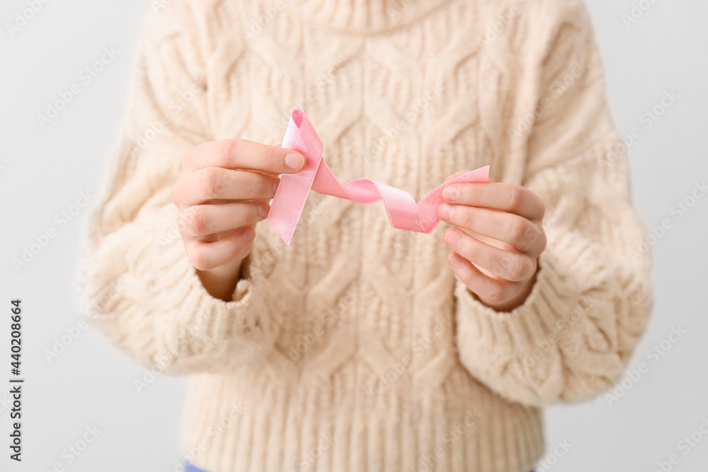 Woman with pink ribbon on light background. Breast cancer concept