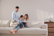 © New Africa - Family with little daughter using tablet on sofa in living room