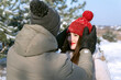 Portrait of couple in love in winter outside. Guy straightens his beloved girl hat.