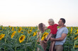 Portrait of young family on sunflower field background. Mom dad and son.