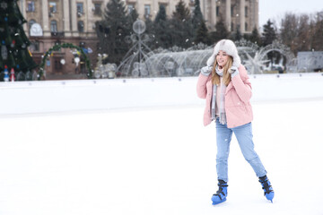 Wall Mural - Happy woman skating along ice rink outdoors. Space for text