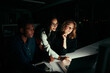 © StratfordProductions - Group of diverse business people working overtime in dark office using laptop