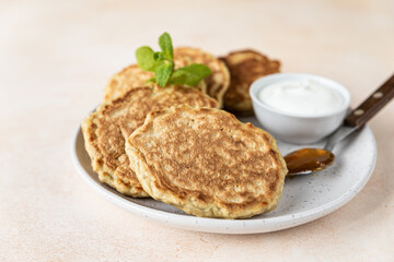 Wall Mural - Tasty oatmeal pancakes served with jam and natural yogurt on ceramic plate, light concrete background.