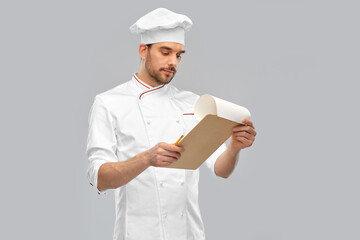 Wall Mural - cooking, culinary and people concept - male chef with clipboard and pencil over grey background