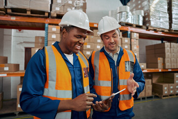 Wall Mural - Happy industrial workers in white hardhat and protective vest looking at digital tablet