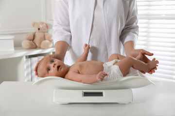 Doctor weighing cute baby in clinic, closeup