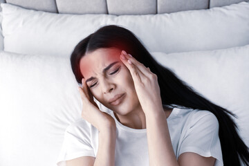 Wall Mural - Young woman suffering from migraine in bed, above view