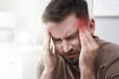Young man suffering from migraine at home, closeup