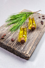 Spa products and coniferous aromatherapy concept with small glass bottles of essential cedar oil on old wooden board.