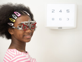 African girl putting optical trial frame to determine visual acuity. health care, medicine, people, eyesight and technology concept.