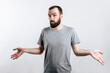 © Daria Lukoiko - Portrait of a cheerful young man smiling while looking at the camera, throwing up his hands to the sides from ignorance on a white background with a place for advertising mockup