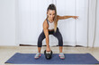 © Juan Algar - Active woman lifting kettlebell during workout