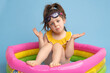 © ADDICTIVE STOCK - Confused little girl sitting in inflatable swimming ring and shrugging shoulders