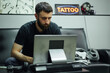 © ADDICTIVE STOCK - Serious man sketching on computer in tattoo salon