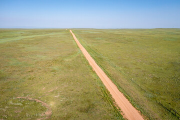 Wall Mural - dirt remote road going through green prairie, Pawnee National Grassland in Colorado, aerial view