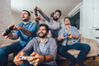 © Mediteraneo - Smiling male friends playing video games at home