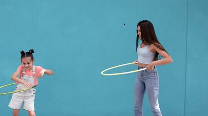 Wall Mural - Teenage girl and little sister playing with hula hoops in the city 