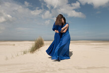 Mother And Daughter In Blue Dress In Loving Embrace On Beach
