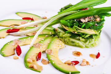 Wall Mural - Salad with chuka seaweed, avocado, cucumber, sesame seeds, pine nuts on a white plate