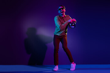 Poster - Full length photo of funny young positive man dance good mood hold disco ball isolated on neon background