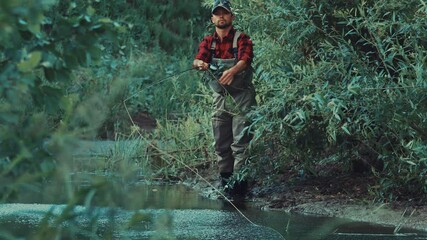 Wall Mural - Fly fishing. Angler fishing on the bushy coast and casts the line downstream the narrow creek