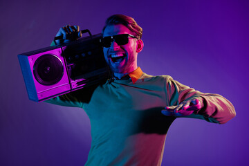 Poster - Photo portrait of man smiling in sunglass keeping boom box on shoulder enjoying music isolated violet color background