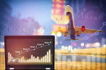 Stack of coins and five years growth graph on computer laptop on aircraft transportation background. Airplane business recovery after covid-19 impact economic idea