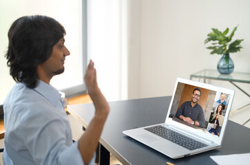 Wall Mural - Indian man using computer application for distance video communication with coworkers, greeting webinar participants, meeting online, looking at the laptop screen with diverse people profiles