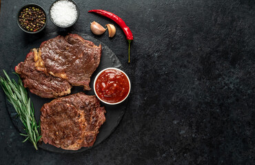 Two grilled ribeye steaks on stone background with copy space for your text