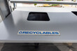 view of a covered, grey and black outdoor trash bin labelled for recyclables only
