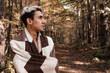 A young and handsome guy walks in the morning through the woods wrapped in a blanket. The body of a man in a blanket.