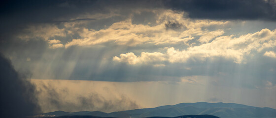 Wall Mural - the sun's rays shine through the clouds over the carpathian mountains