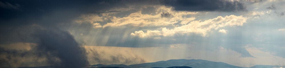 Wall Mural - the sun's rays shine through the clouds over the carpathian mountains