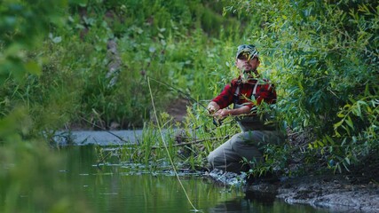 Wall Mural - Fly fishing. Angler fishing on the bushy coast and casts the line downstream the narrow creek