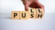 Pull or push symbol. Businessman turns wooden cubes and changes the word 'push' to 'pull'. Beautiful white background, copy space. Business and pull or push concept.